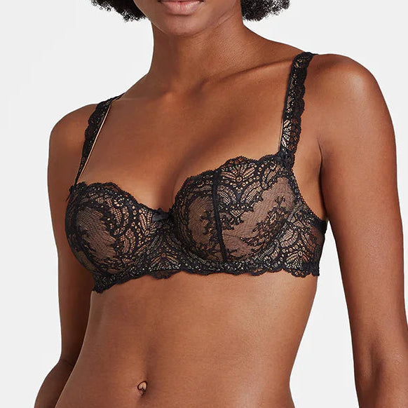 Woman wearing black lace lingerie against a plain background