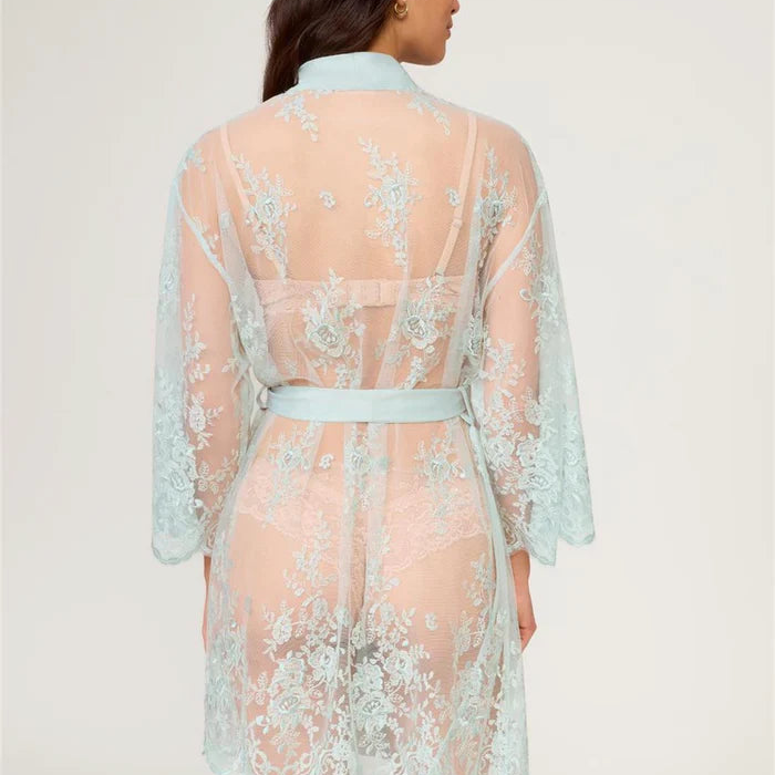 Woman wearing a light blue lace robe on a plain background