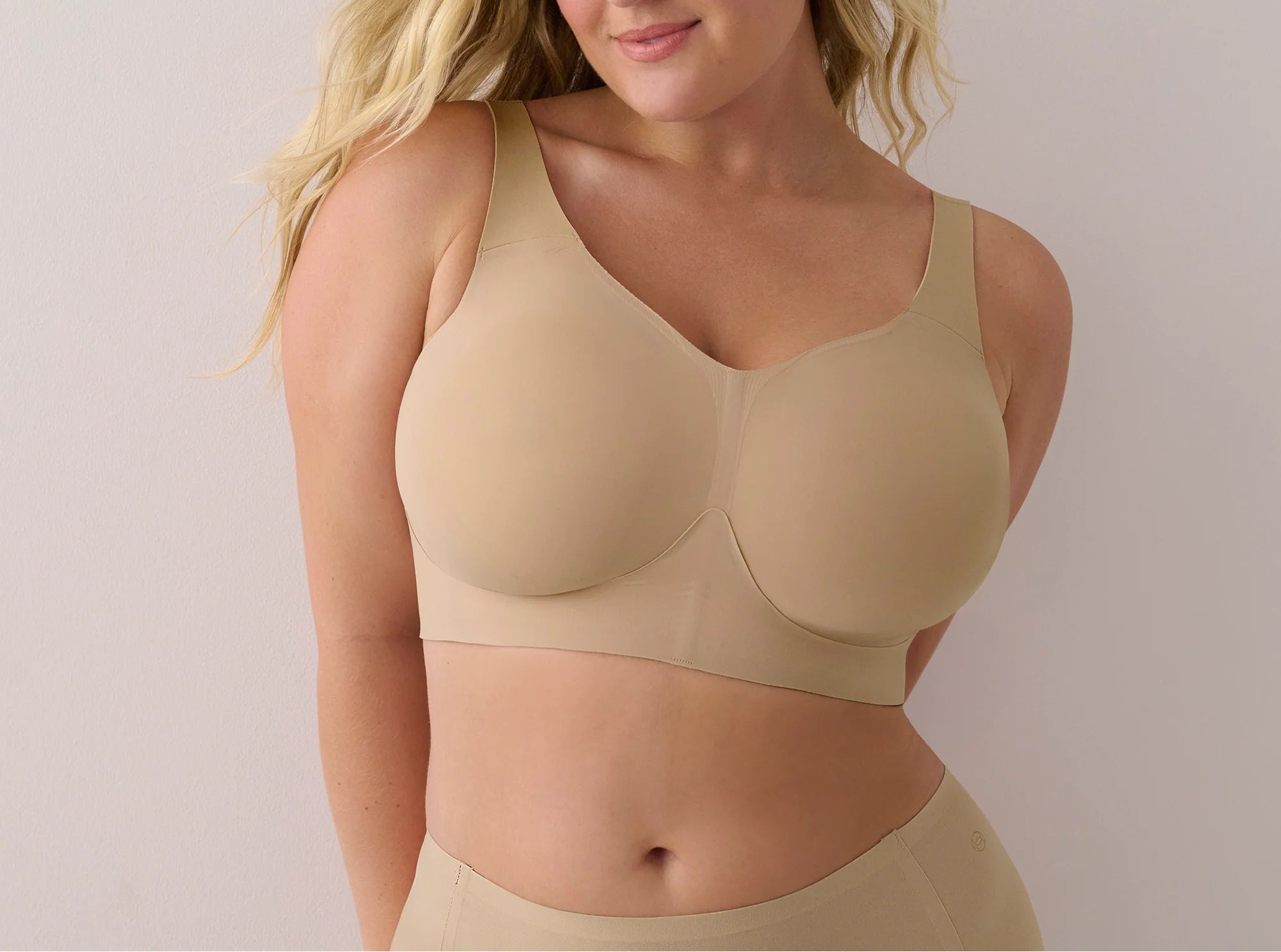 Woman wearing a beige bra and underwear set against a plain background