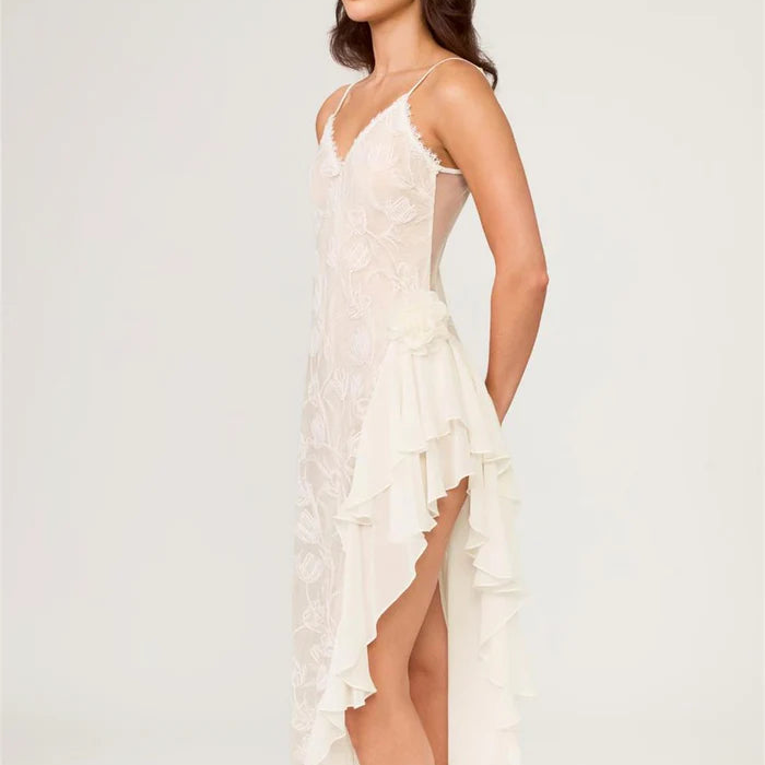 Woman wearing a white lace dress with a high slit on a light gray background