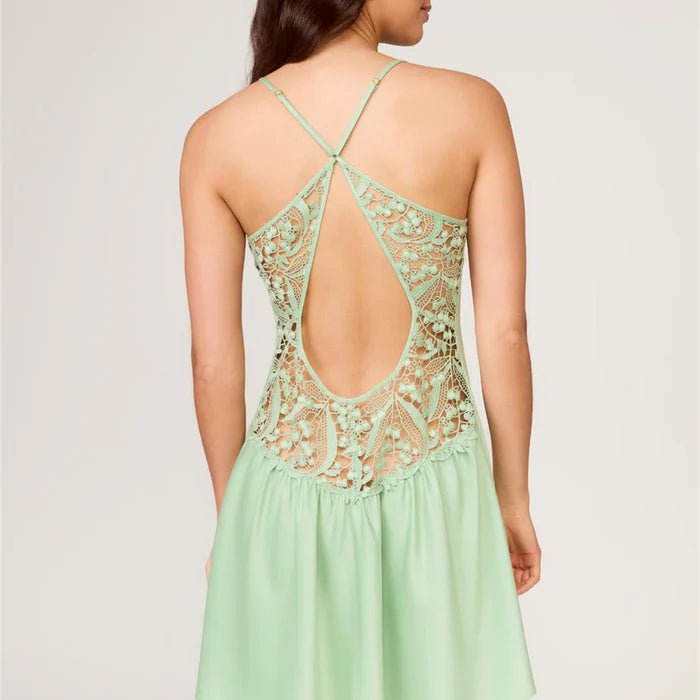 Woman wearing a light green dress with lace detailing on a plain background
