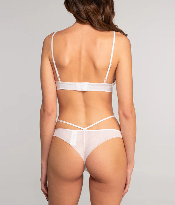 Woman wearing a white lingerie set on a plain background