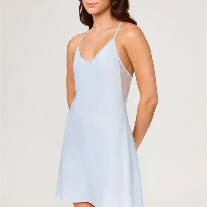 Woman wearing a light blue slip dress against a plain background