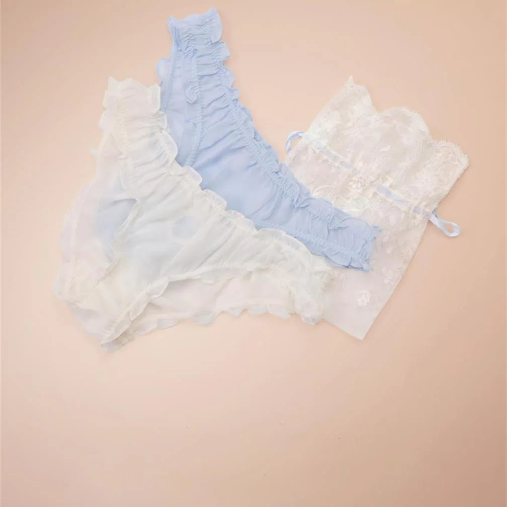 Set of pastel blue and white lace lingerie on a beige background