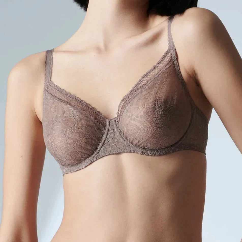 This image displays the Comete Full Cup Bra by Simone Perele, modeled in a sophisticated and stylish manner. The bra features a rich, dark green lace fabric, providing an elegant appearance while offering a comfortable fit.