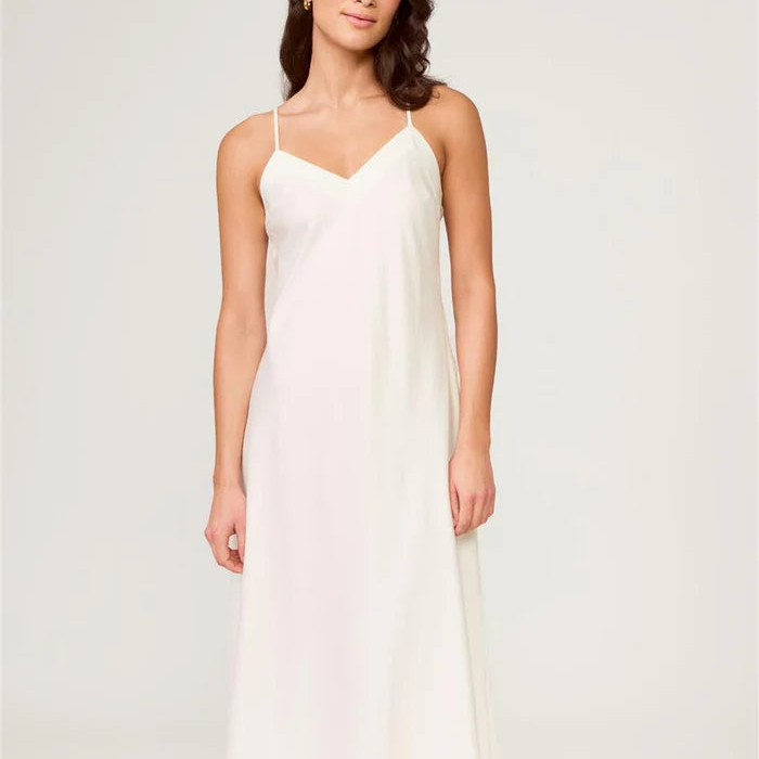 Woman wearing a white slip dress against a plain background
