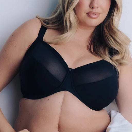 Woman wearing a black bra and panties set against a white background