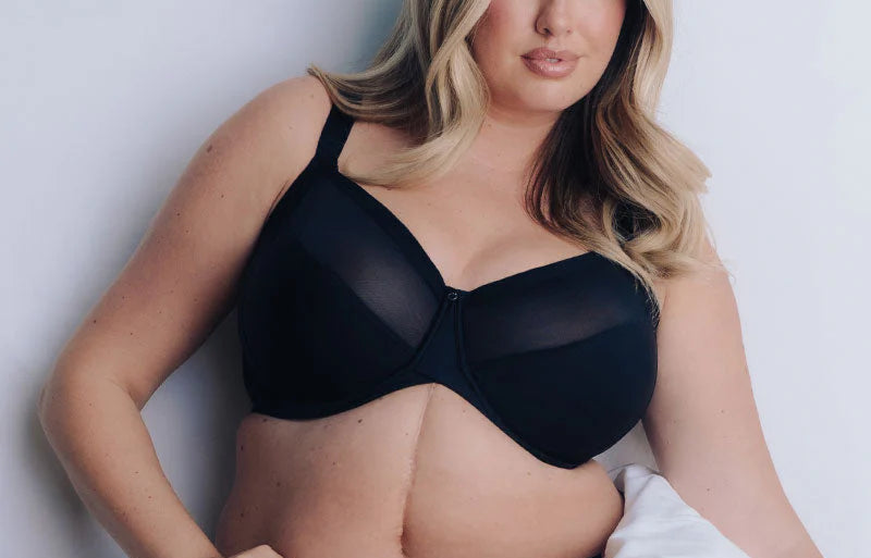 Woman wearing a black bra and panties set against a white background