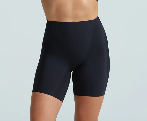 Person wearing a black sports bra and high-waisted shorts on a light gray background
