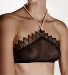 Black lace bralette worn by a model with a pearl necklace on a plain background