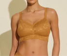 Woman wearing a mustard yellow lace bralette against a beige background