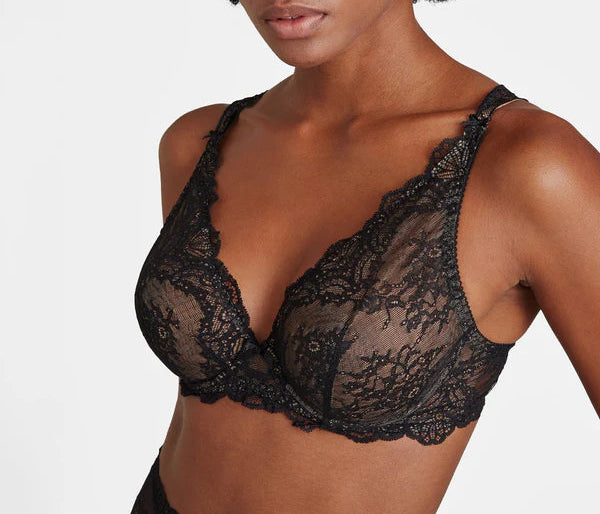 Woman wearing a black lace bra against a plain background