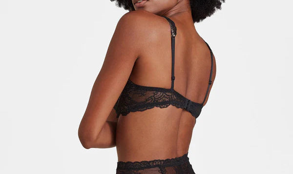 Woman wearing a black lace lingerie set on a plain background
