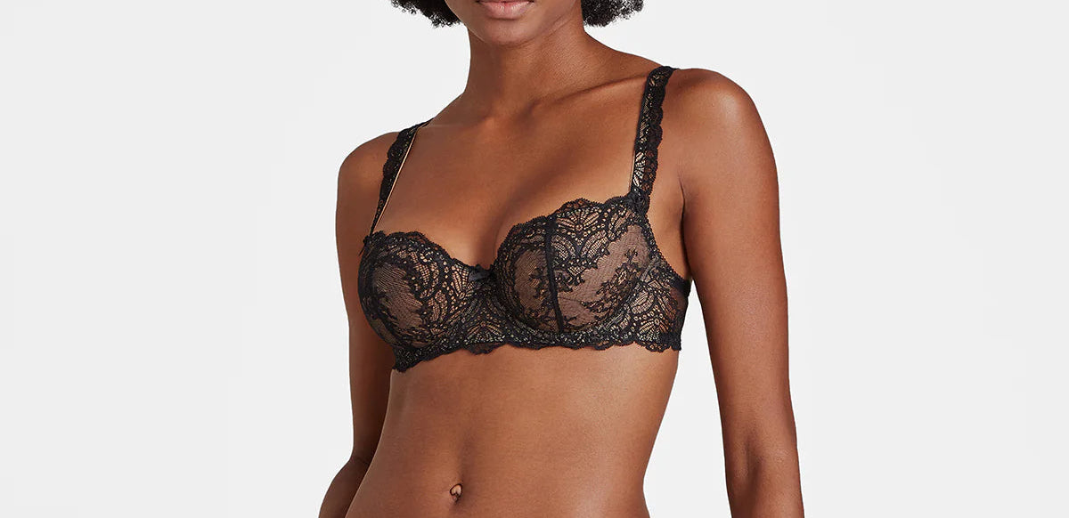Woman wearing black lace lingerie against a plain background