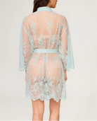 Woman wearing a light blue lace robe on a plain background