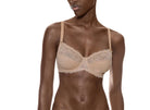 Woman wearing a beige lace bra and panties set on a white background