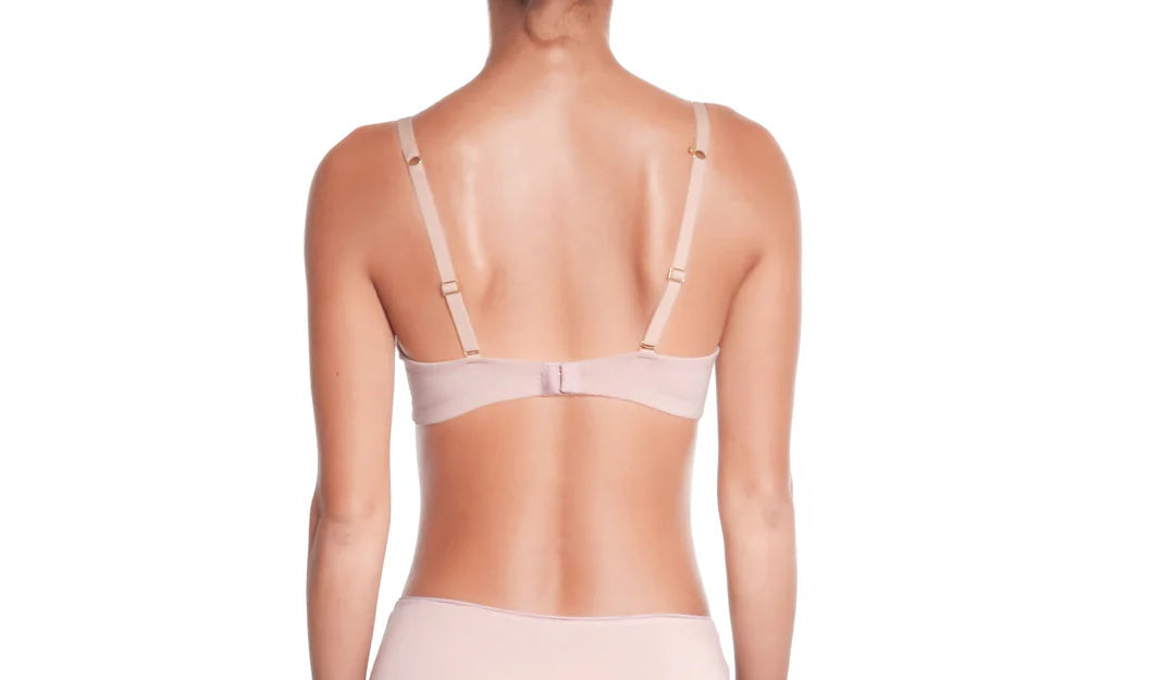 Woman wearing a sheer beige lingerie set on a white background