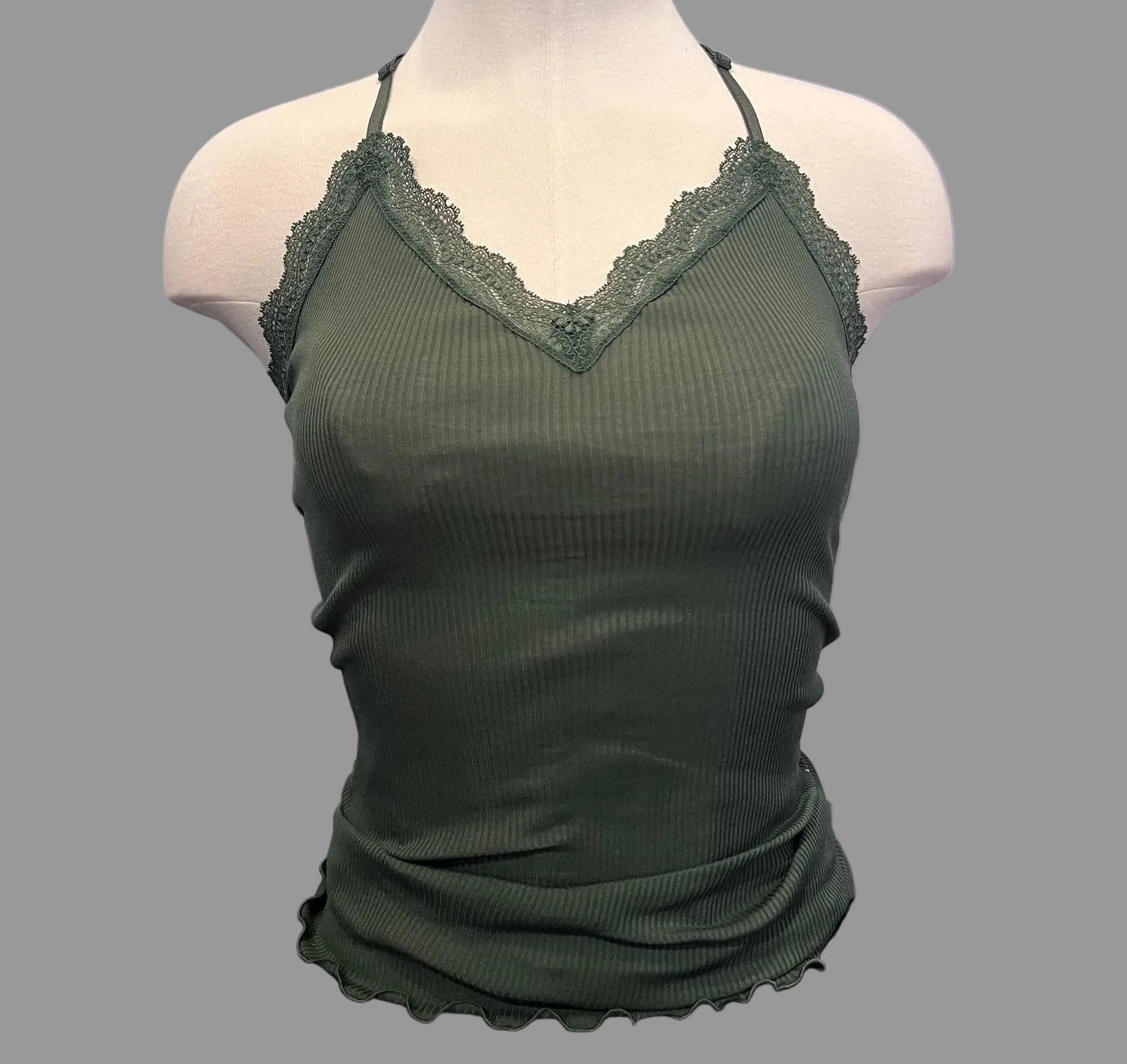 Green lace-trimmed top on a mannequin against a neutral background