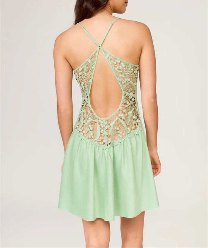 Woman wearing a light green dress with lace detailing on a plain background