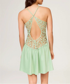 Woman wearing a light green dress with lace detailing on a plain background