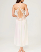 Woman wearing a white lace dress with an open back on a light gray background