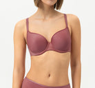 Woman wearing a maroon bra and underwear set on a light gray background