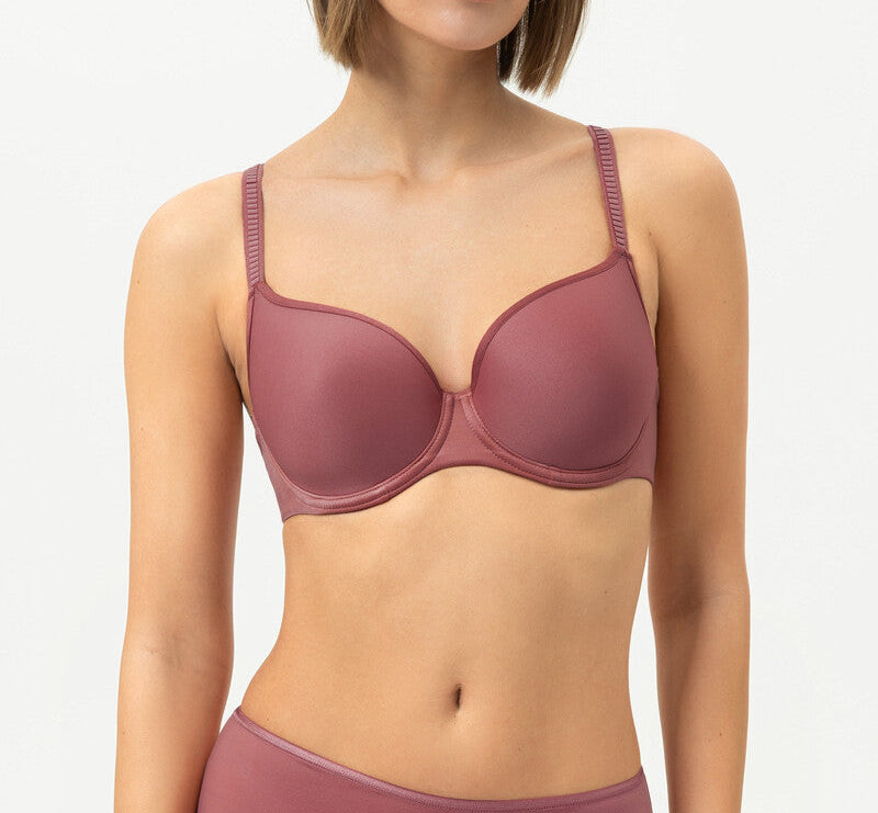 Woman wearing a maroon bra and underwear set on a light gray background