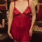 Woman wearing a red lace nightgown in a dressing room setting.