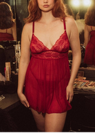 Woman wearing a red lace nightgown in a dressing room setting.