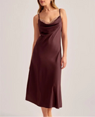 Woman wearing a burgundy slip dress on a light gray background