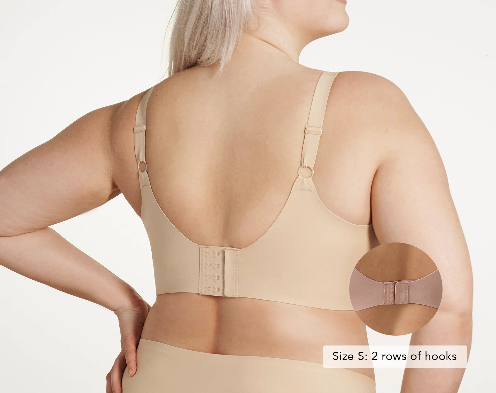 Woman wearing a beige bra with a close-up of the back and arm area on a white background.