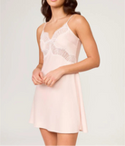 Woman wearing a light pink dress with lace details on a plain background