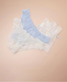 Set of pastel blue and white lace lingerie on a beige background