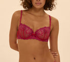 Woman wearing a pink lace bra and panties set on a beige background