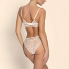 Woman wearing a white lace lingerie set on a beige background
