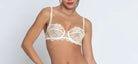 Woman wearing a white lace lingerie set on a plain background