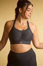 Woman wearing a black sports bra and leggings on a beige background
