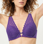 Woman wearing a purple bralette against a plain background