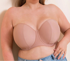 Woman wearing a beige strapless bra against a plain background