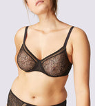 This image displays the Comete Full Cup Bra by Simone Perele, modeled in a sophisticated and stylish manner. The bra features a rich, dark green lace fabric, providing an elegant appearance while offering a comfortable fit.