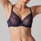 This image displays the Comete Full Cup Bra by Simone Perele, modeled in a sophisticated and stylish manner. The bra features a rich, dark green lace fabric, providing an elegant appearance while offering a comfortable fit.