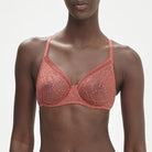 This image displays the Comete Full Cup Bra by Simone Perele, modeled in a sophisticated and stylish manner. The bra features a rich, dark green lace fabric, providing an elegant appearance while offering a comfortable fit.