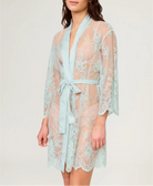 Woman wearing a light blue lace robe against a white background