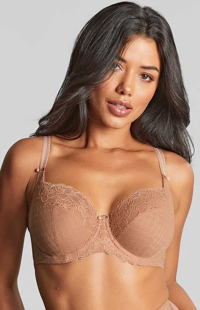 Woman wearing a beige lace bra against a gray background