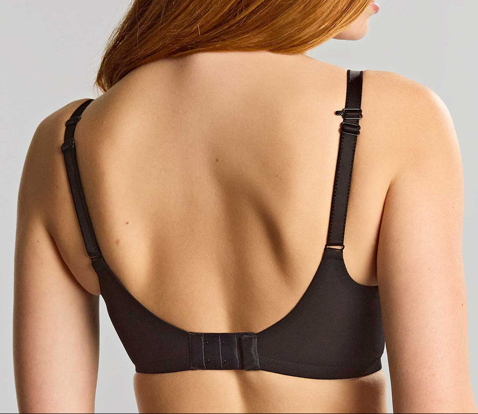 Woman wearing a black bra against a plain background