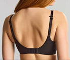 Woman wearing a black bra against a plain background