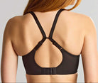 Person wearing a black bralette with thin straps on a plain background