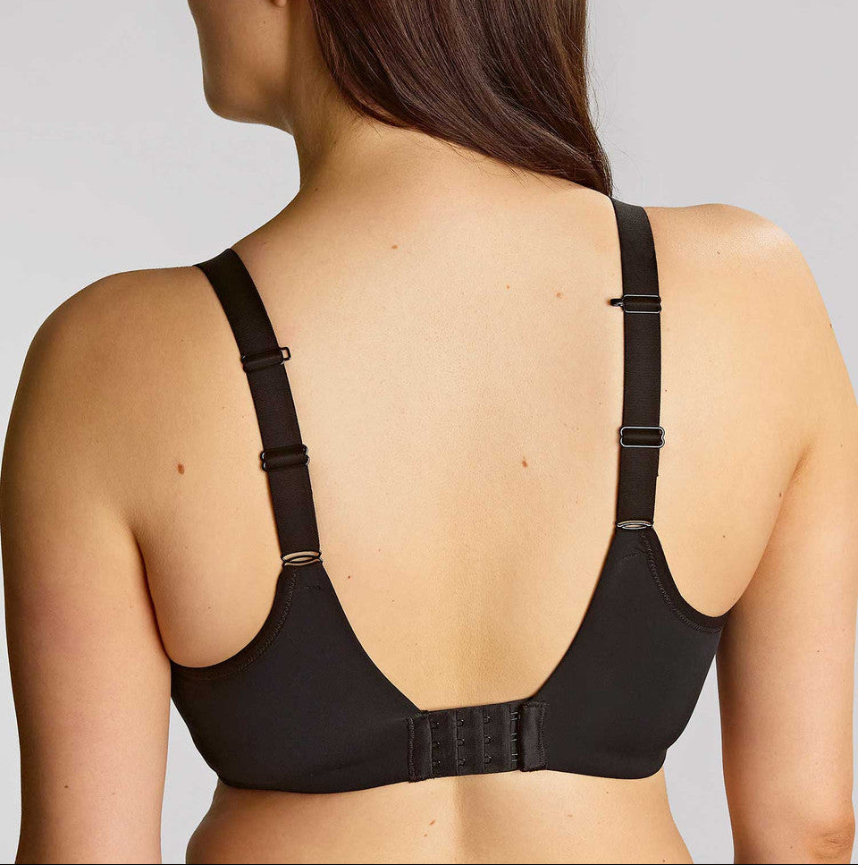Woman wearing a black bra against a plain background