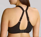 Woman wearing a black bralette with thin straps on a plain background