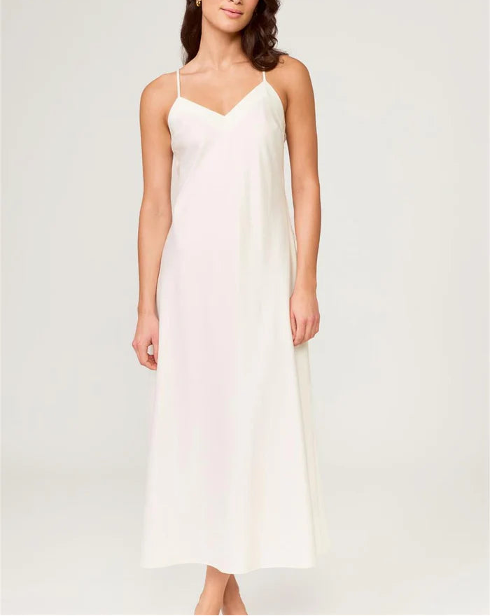 Woman wearing a white slip dress against a plain background
